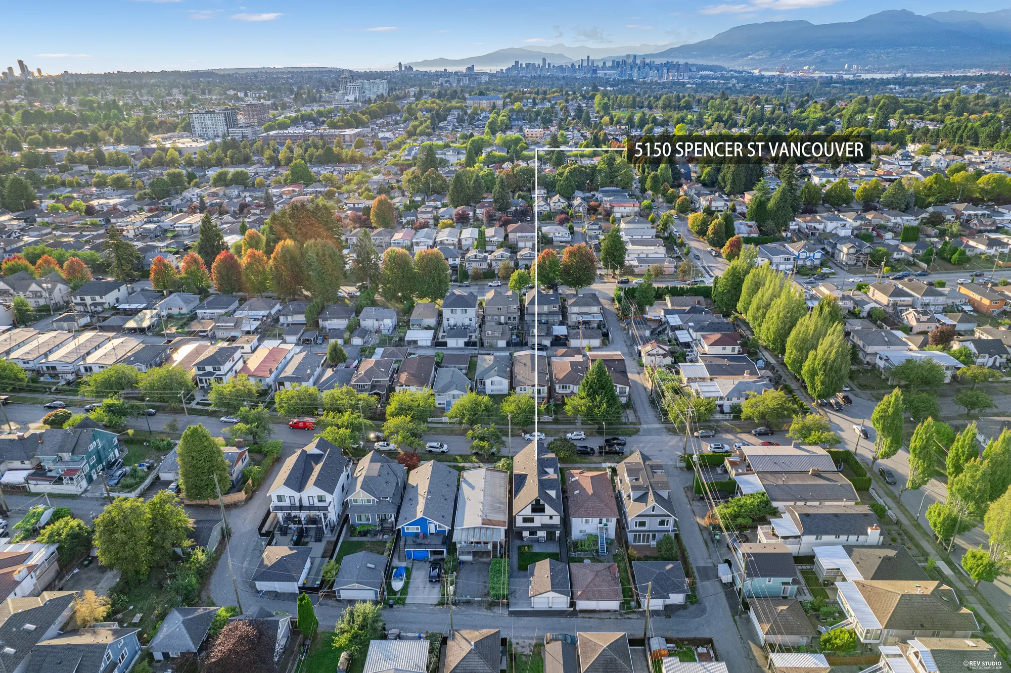 Aerial across the rooftops with the North Shore mountains behind, the property marked