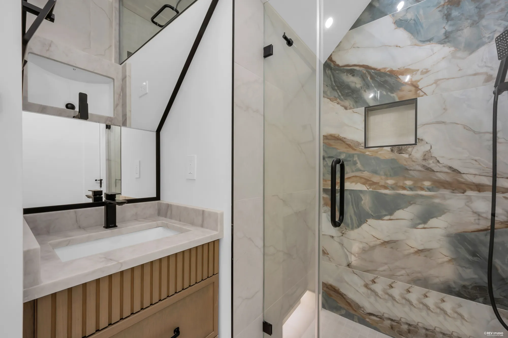 The top-floor bathroom with a stone counter and a black-framed shower