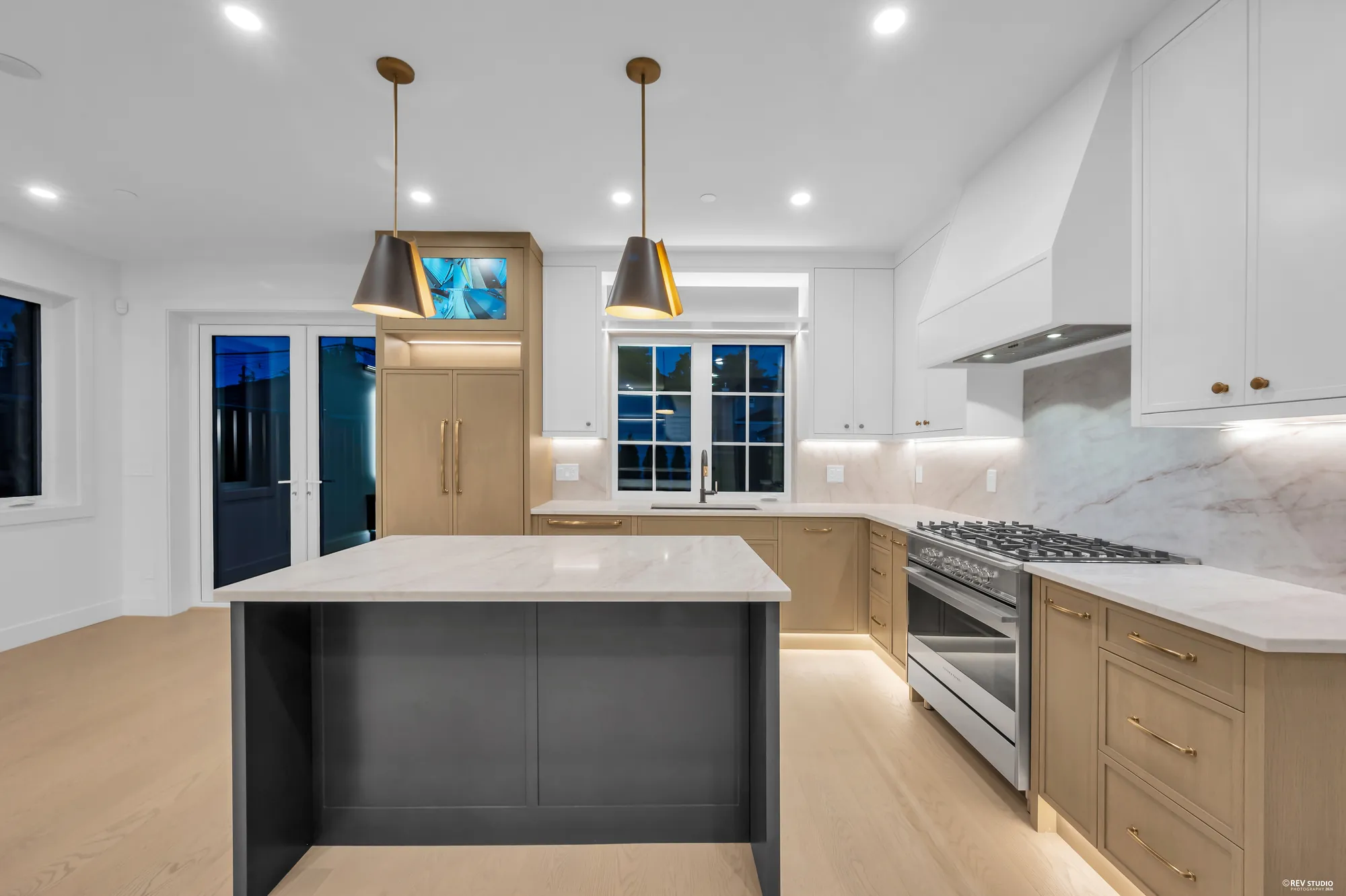 Kitchen with a black island, brass pendants and a range in the run